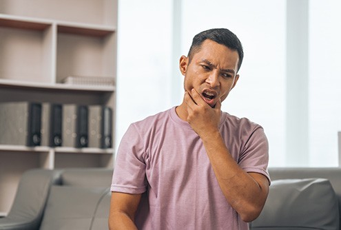 Man in light purple shirt rubbing his jaw