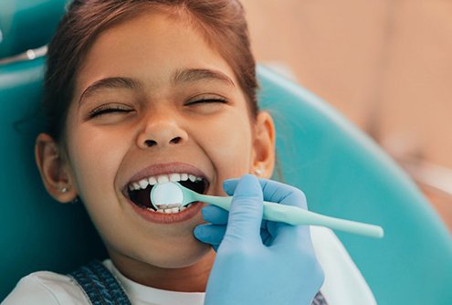 a child smiling while undergoing a dental visit