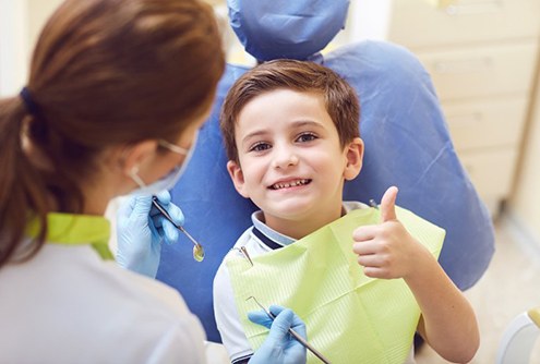 a child giving a thumbs-up while visiting his dentist