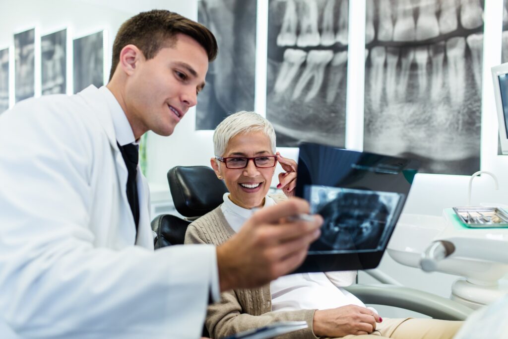 Woman smiling with dentist while reviewing X-ray